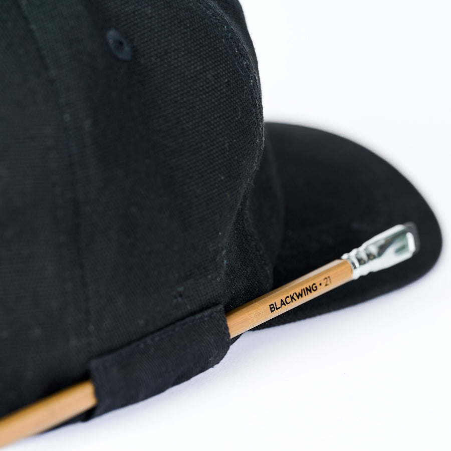 Black cap featuring a pencil loop on the side to hold a Blackwing pencil