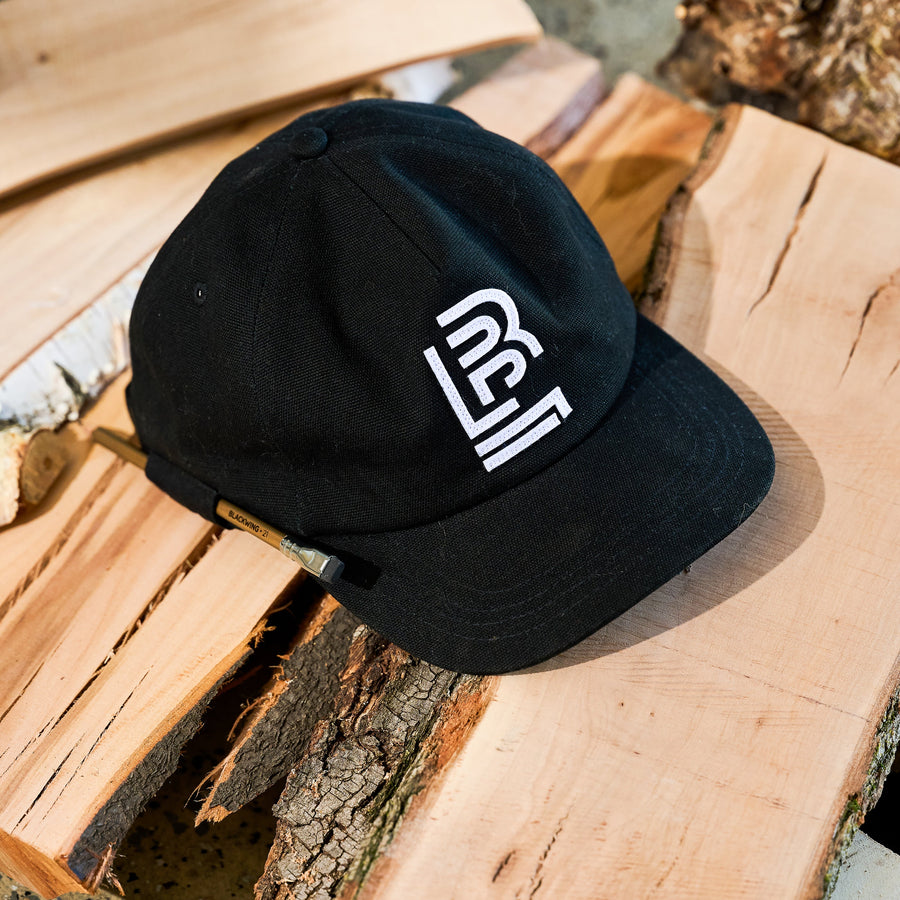 Black canvas cap with a white embroidered Blackwing emblem on front. the cap can hold a Blackwing pencil on the side loop