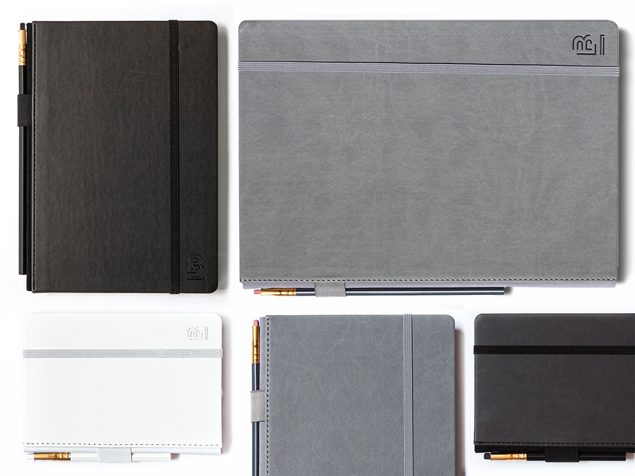 A variety of Small Blackwing Slate Notebooks in white are scattered on a white surface.